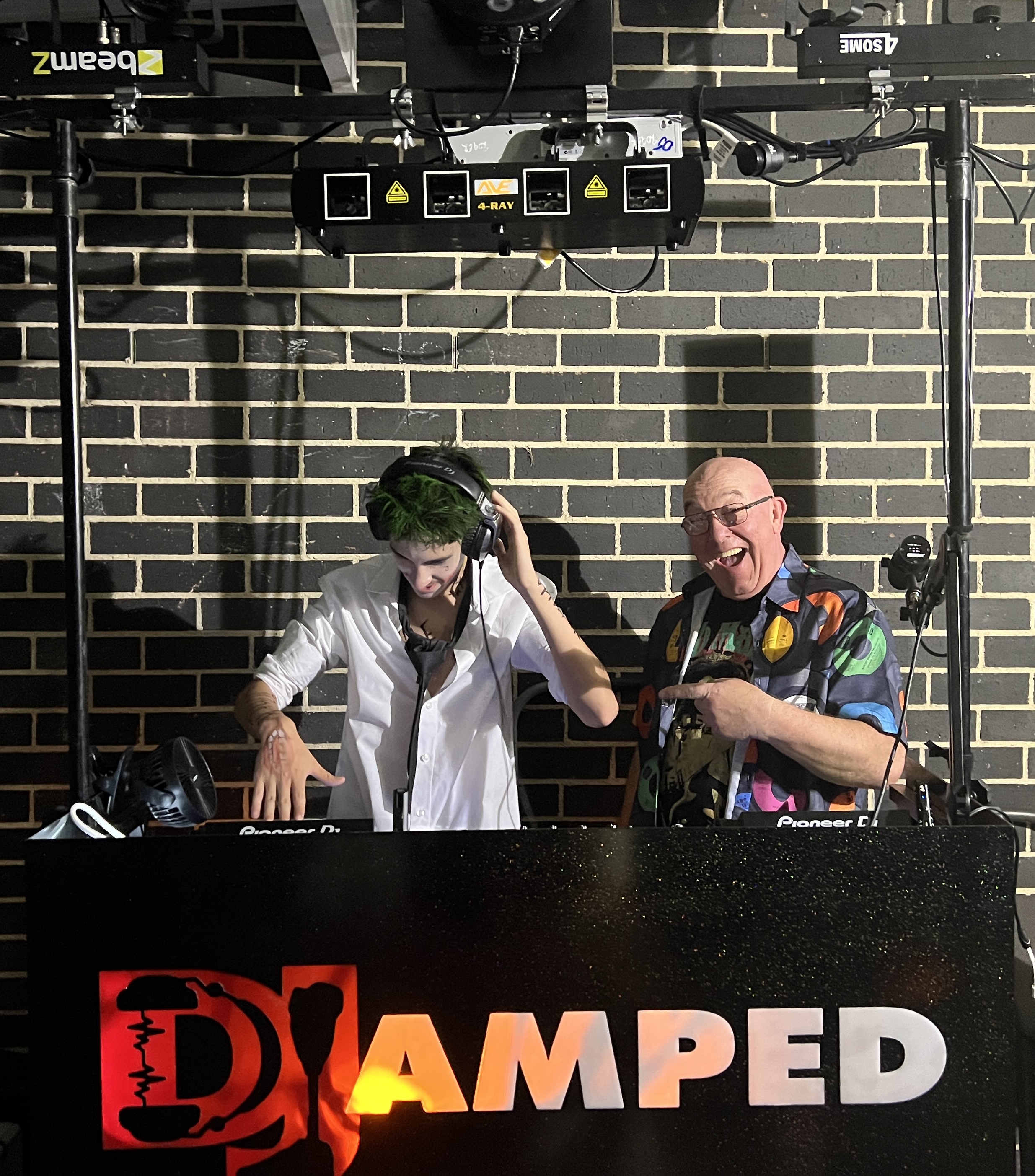Cooper mixing with headphones while AMPT Australia celebrates beside him