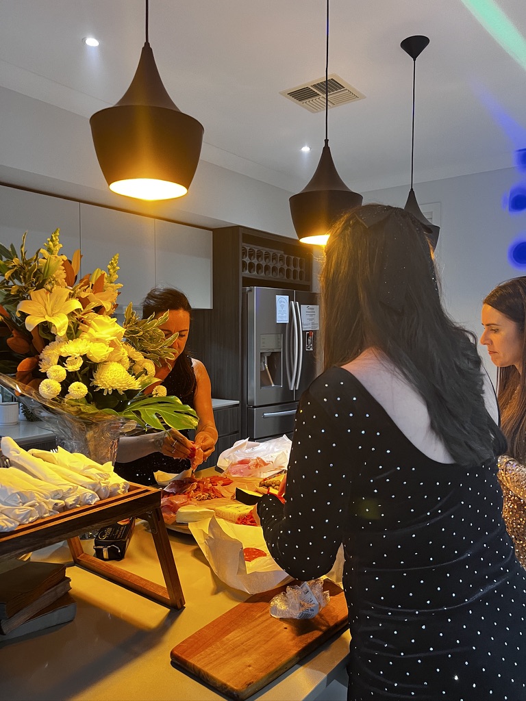Guests preparing food beside a large flower arrangement