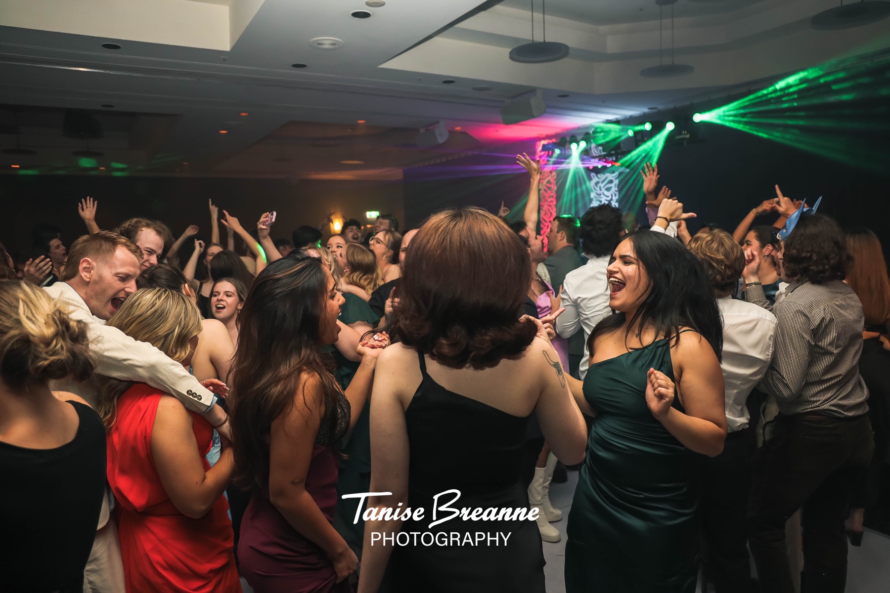 Crowded dance floor under green event lighting at the UOW Law Ball