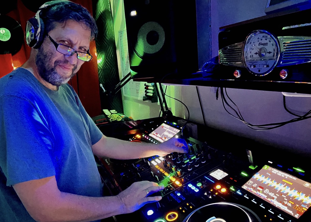 An adult DJ student smiling while working at the decks