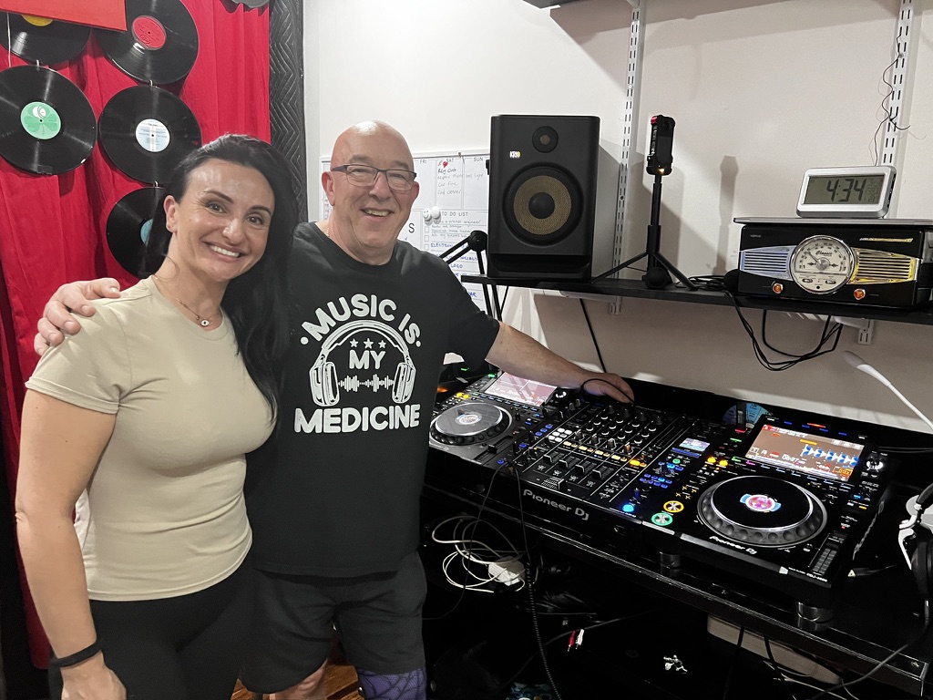 An adult DJ student and AMPT Australia smiling beside the professional decks