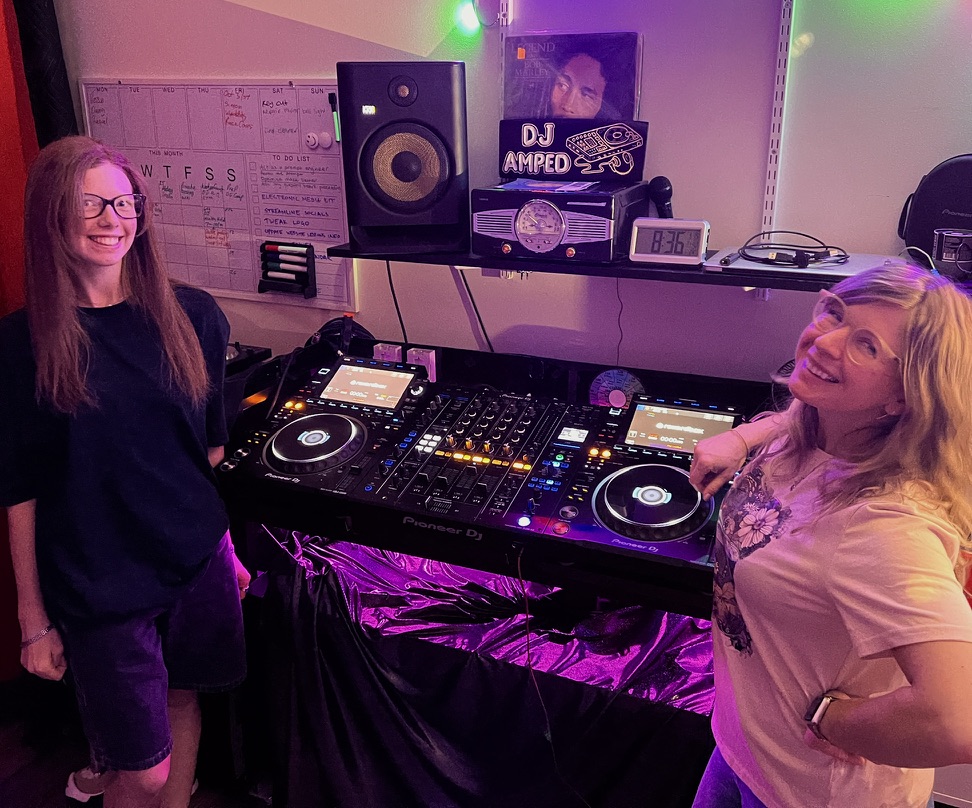 An aunt and niece smiling beside the DJ setup after learning together