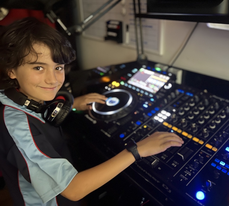 A smiling young DJ learning on Pioneer equipment