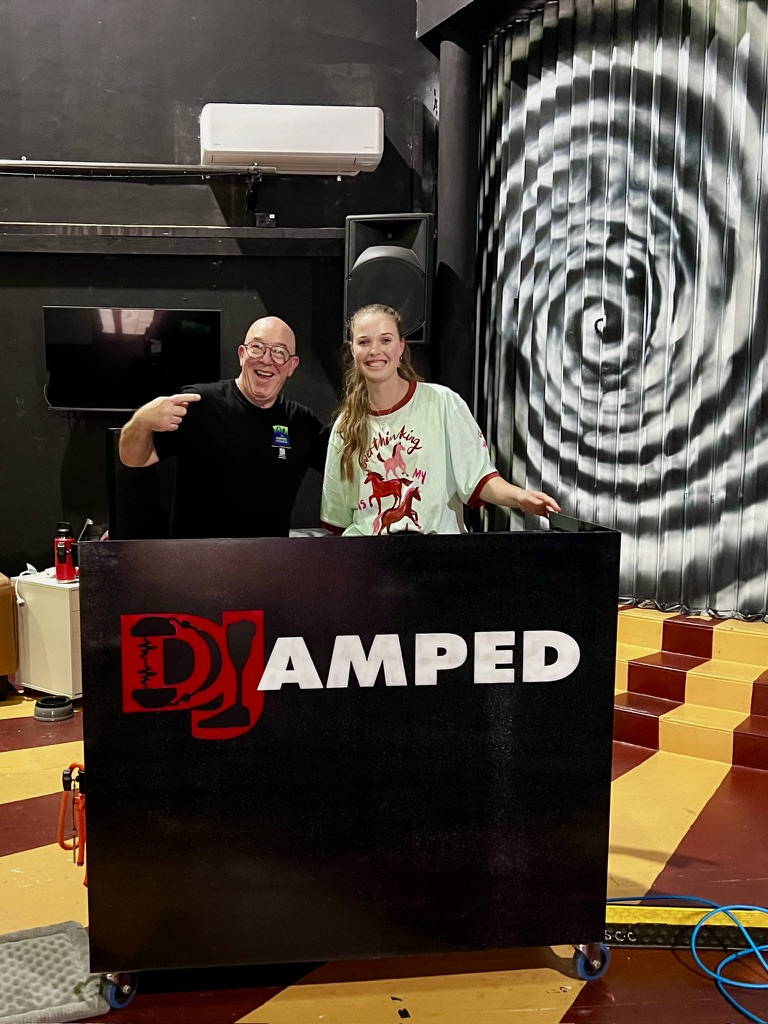A young Youth Week participant and AMPT Australia smiling behind the DJ booth