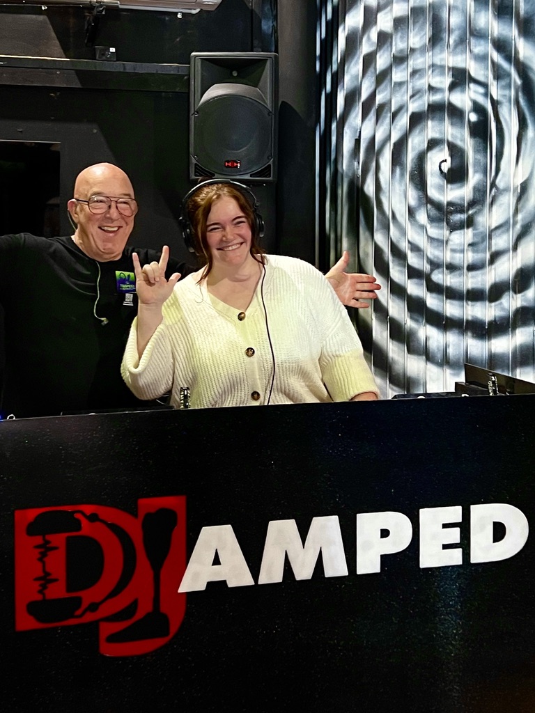 A smiling Youth Week DJ lesson participant wearing headphones beside AMPT Australia