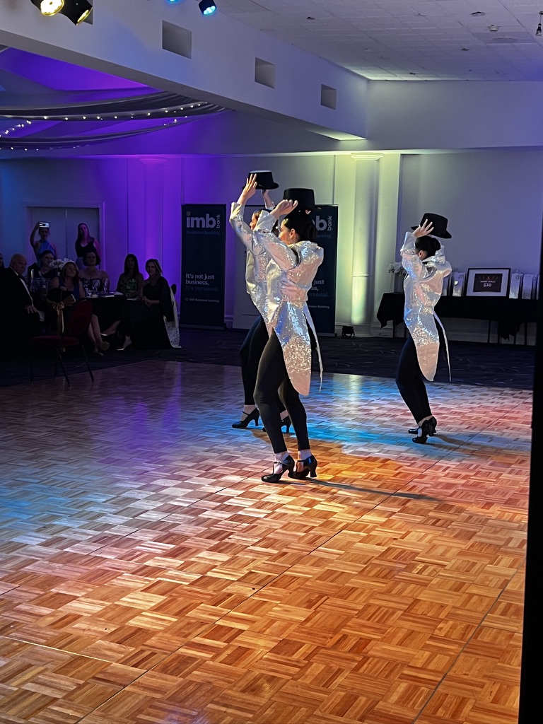Three dancers performing with top hats