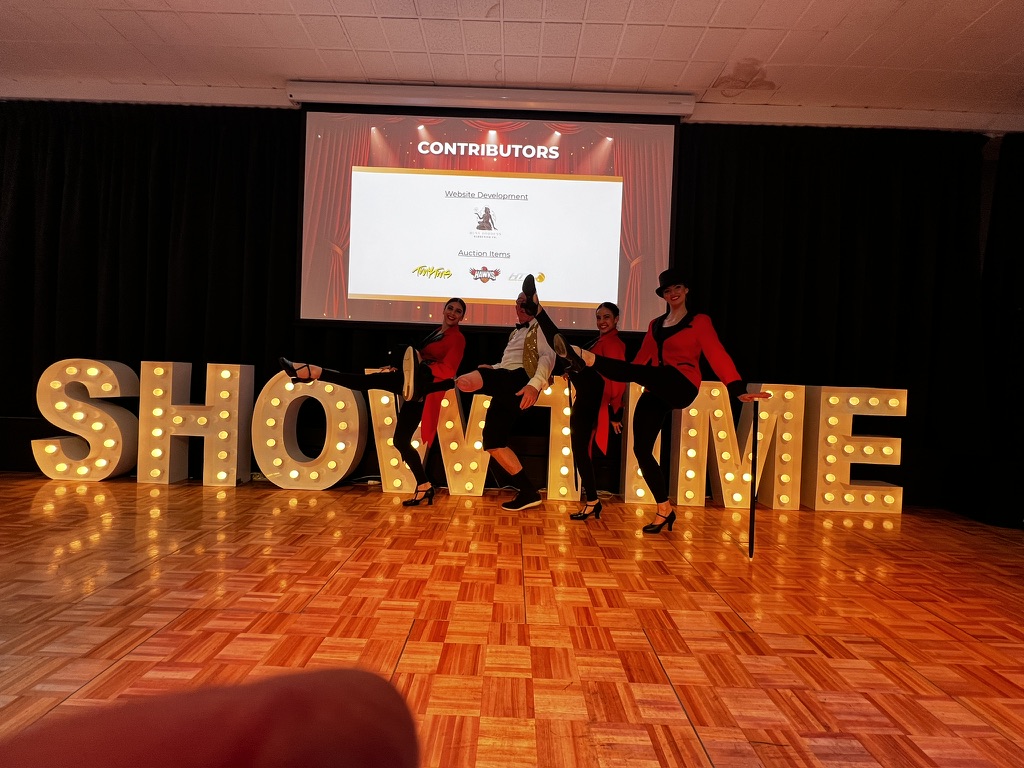 Showtime performers posing in front of illuminated letters