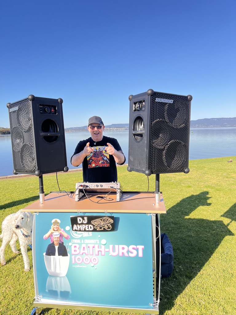 AMPT Australia pointing from behind the Wave FM event DJ booth