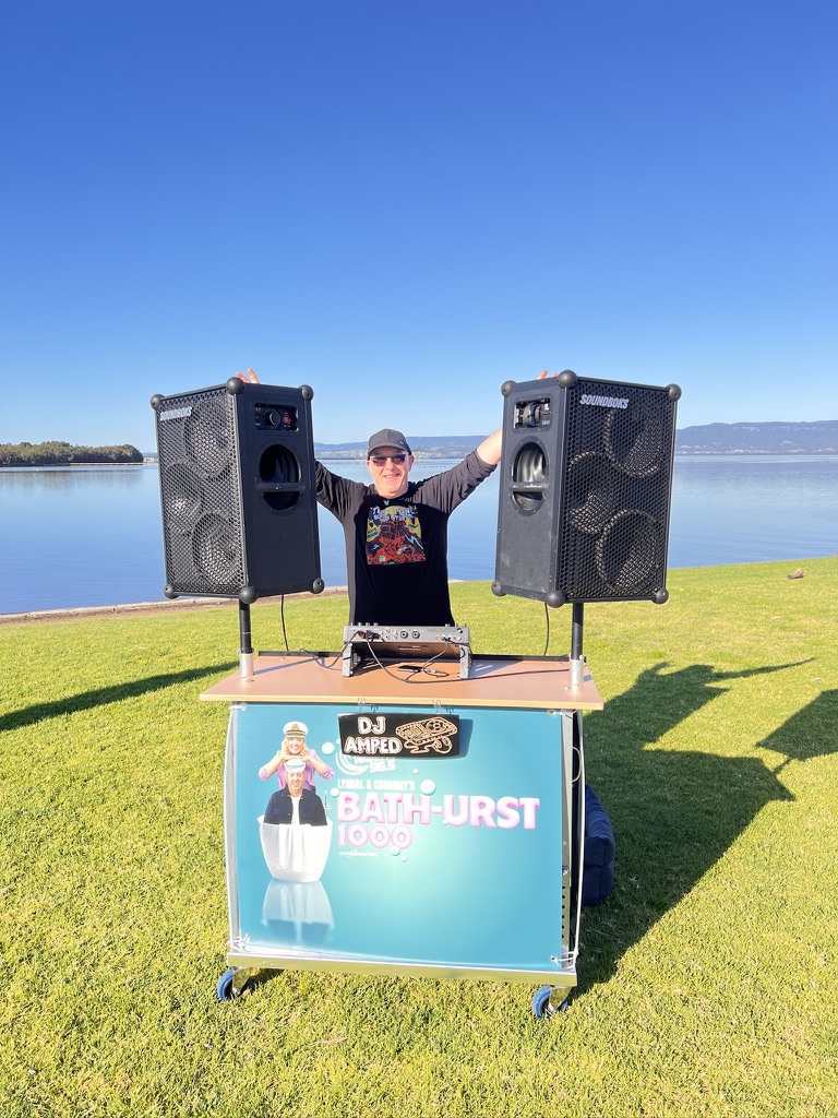 AMPT Australia behind the outdoor AMPT booth with two battery-powered speakers