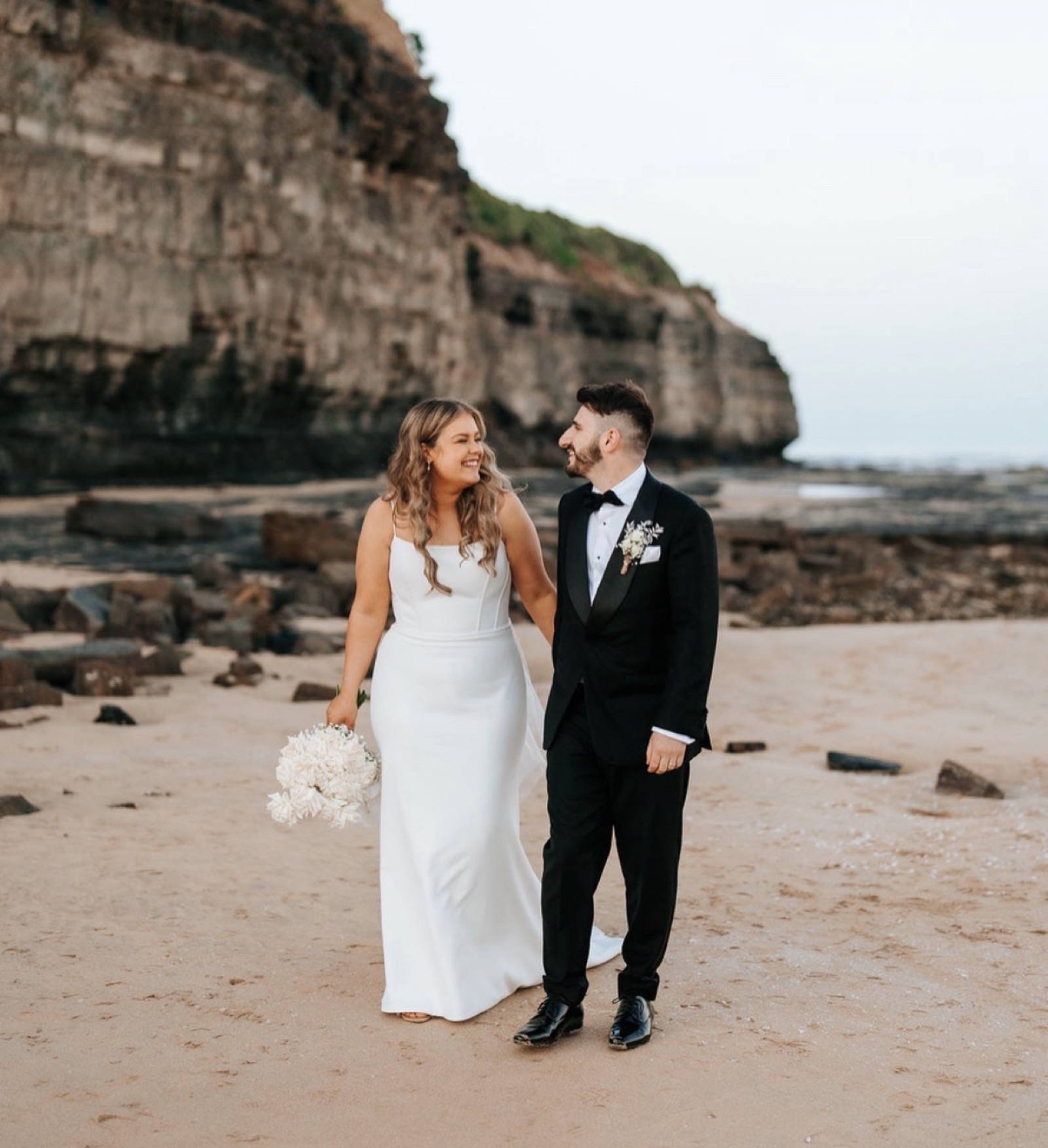 Jonathan and Caitlin smiling together on the beach on their wedding day
