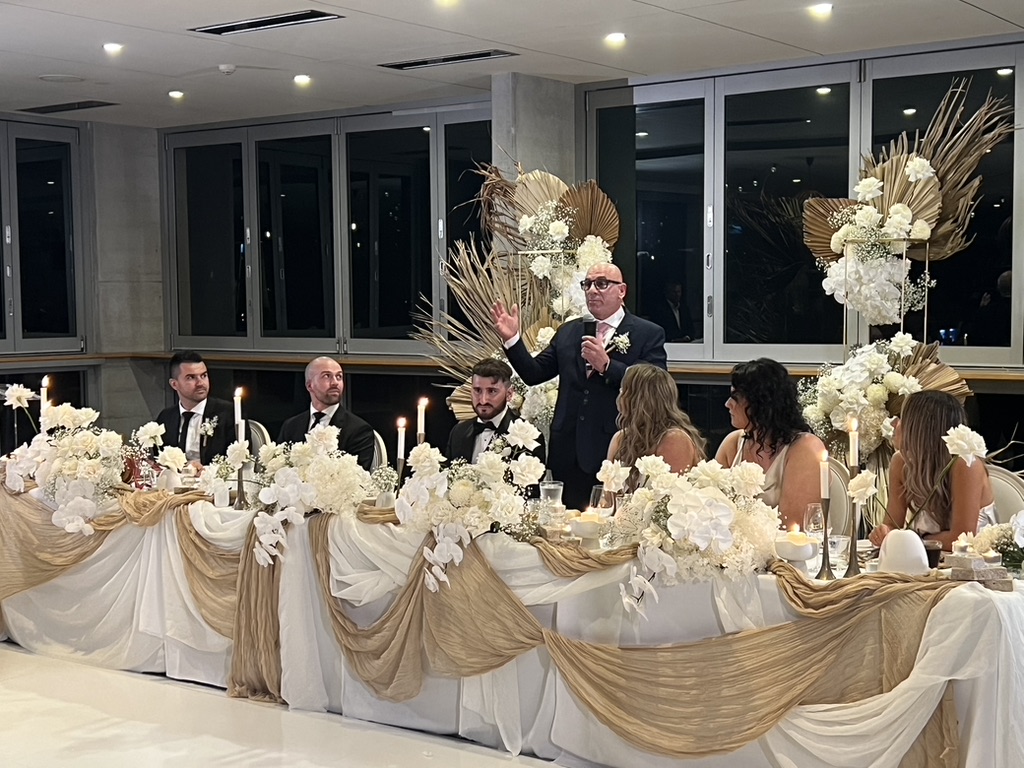 AMPT Australia speaking beside Jonathan and Caitlin at the wedding table