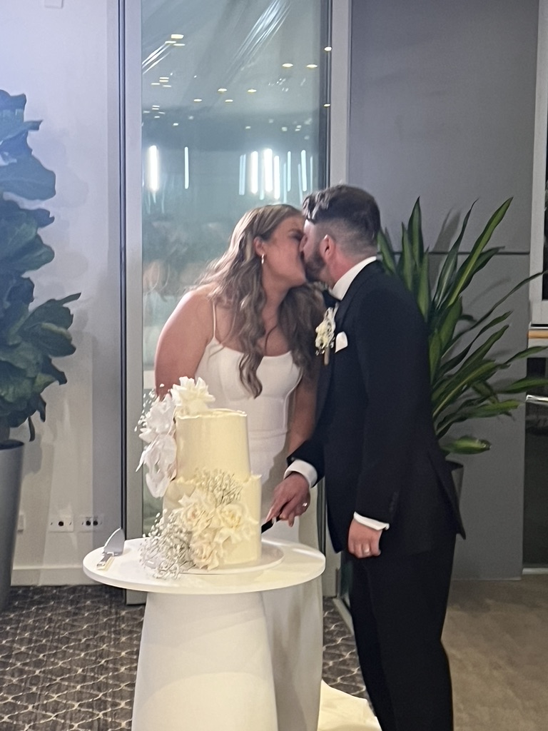 Jonathan and Caitlin kissing beside their wedding cake