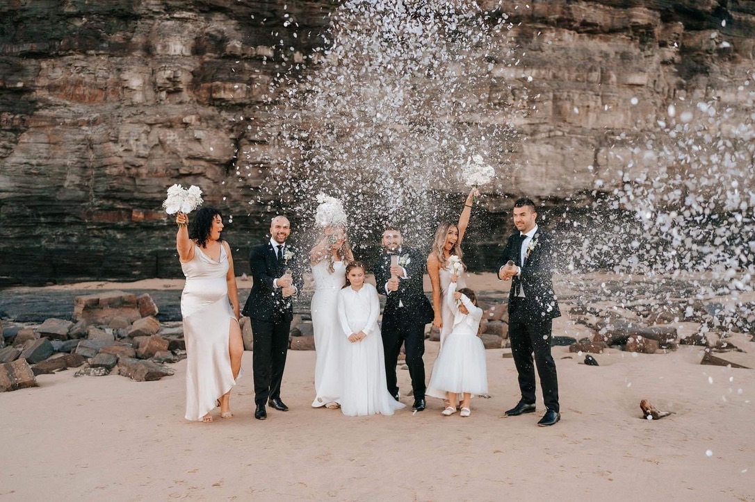 Jonathan and Caitlin’s wedding party celebrating with confetti on the beach