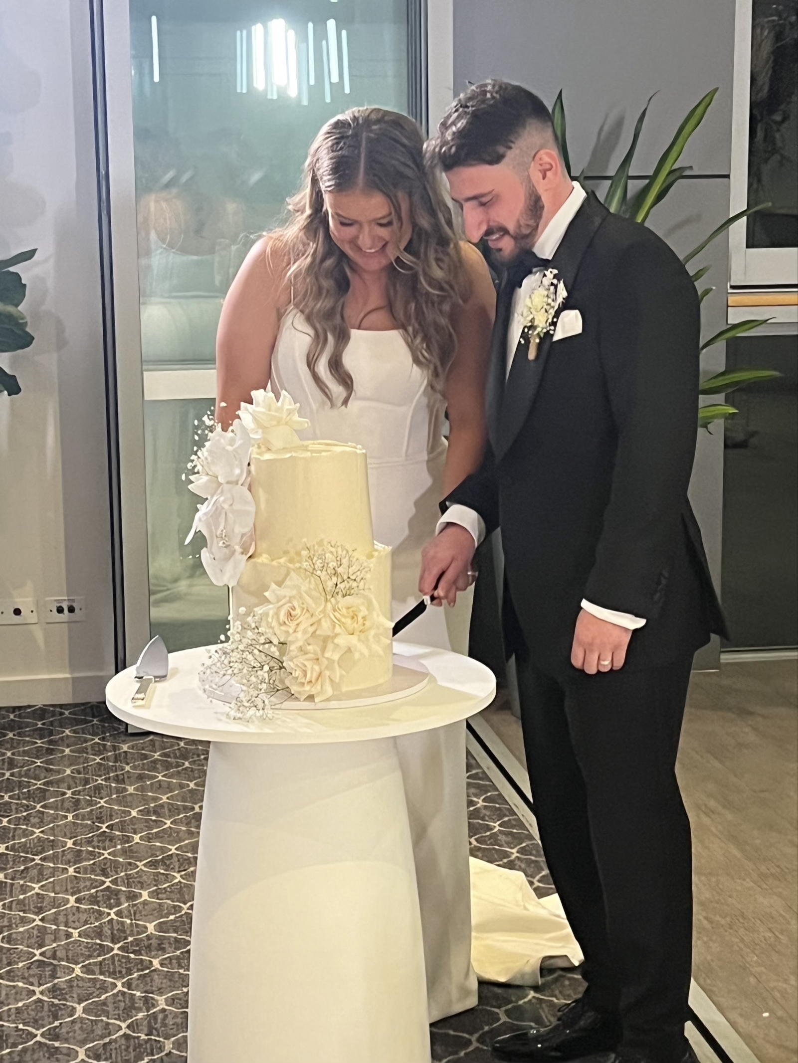 Jonathan and Caitlin smiling together while cutting their wedding cake