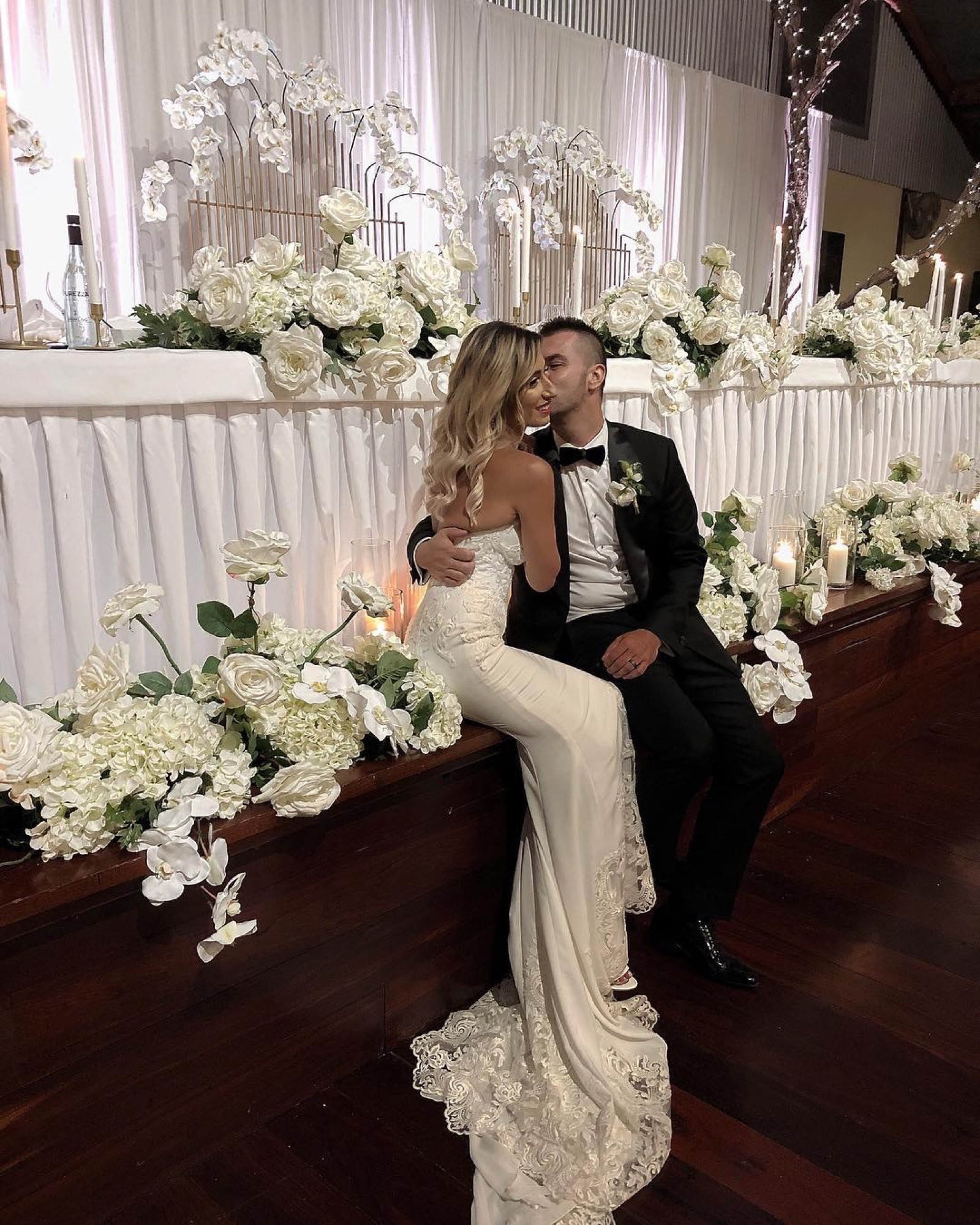 A newly married couple sharing a quiet moment among white reception flowers